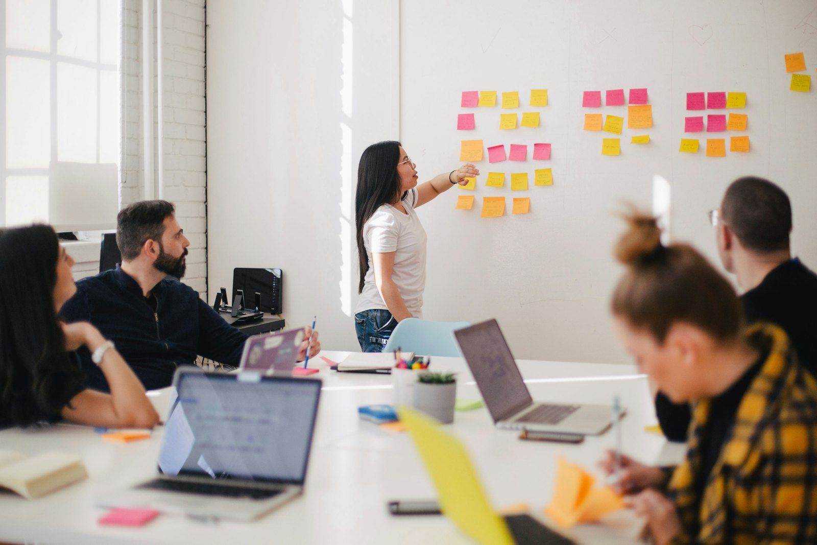 A team meeting around a table with notes on the wall behind them