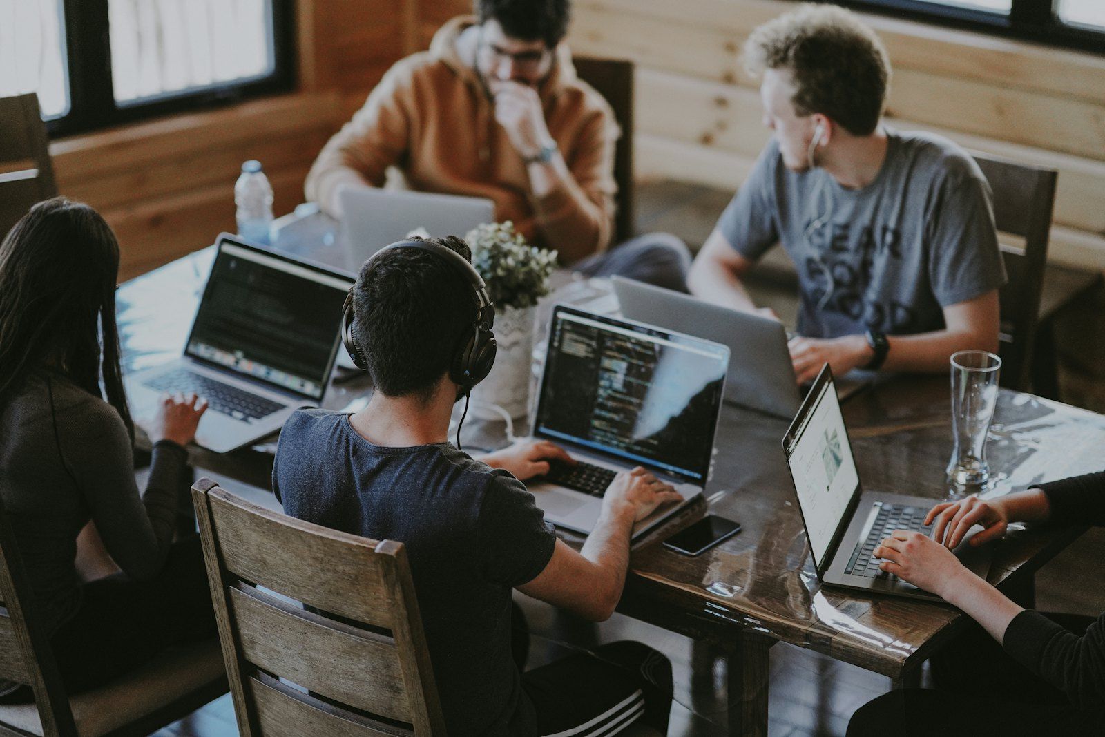 A team of developers working together on laptops around a wooden table