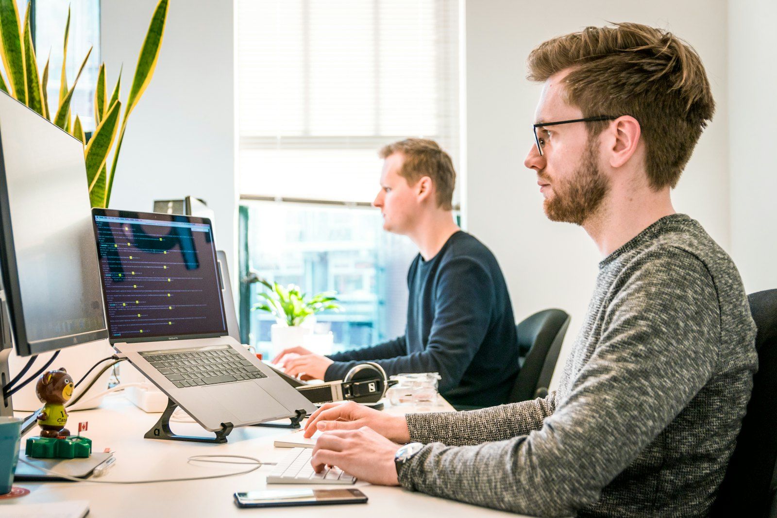 People working at desks with large monitors in a bright office