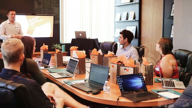 A small team planning around a table with laptops and notebooks