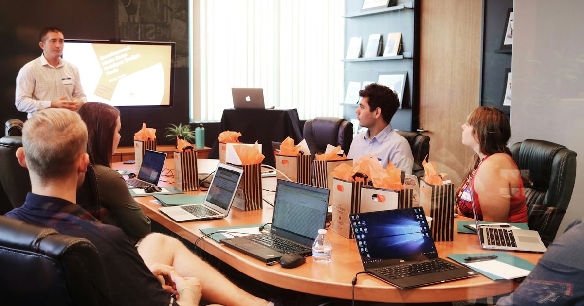 A small team planning around a table with laptops and notebooks