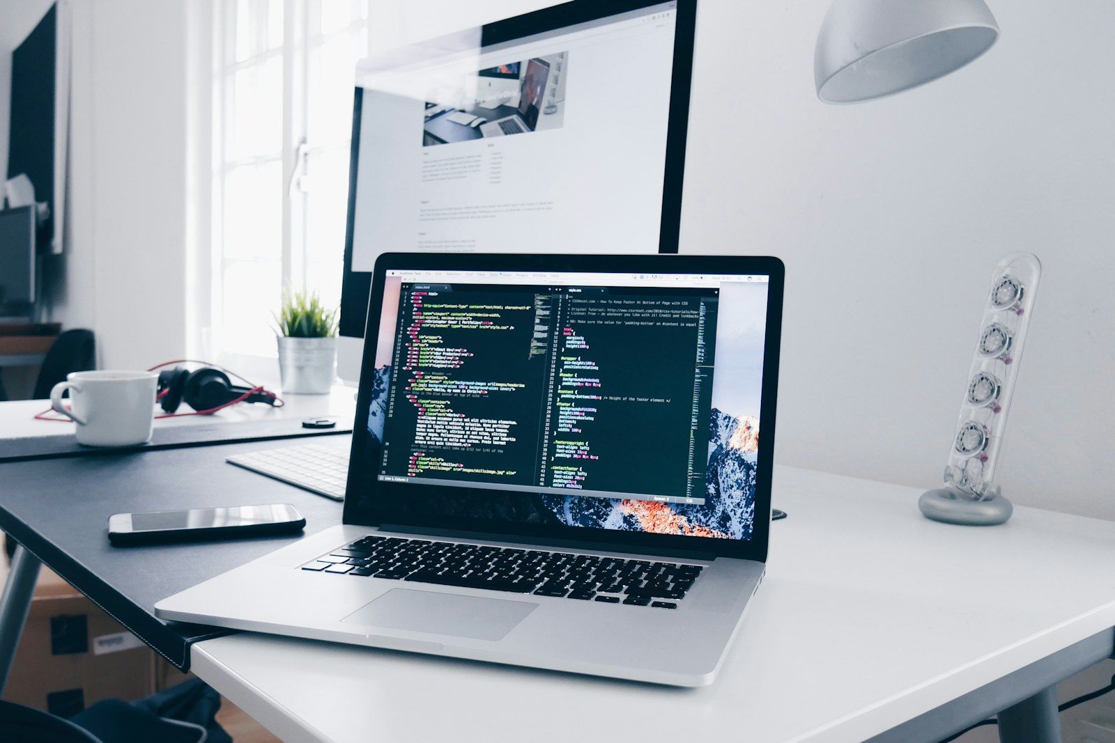 Code on a laptop screen beside a coffee cup